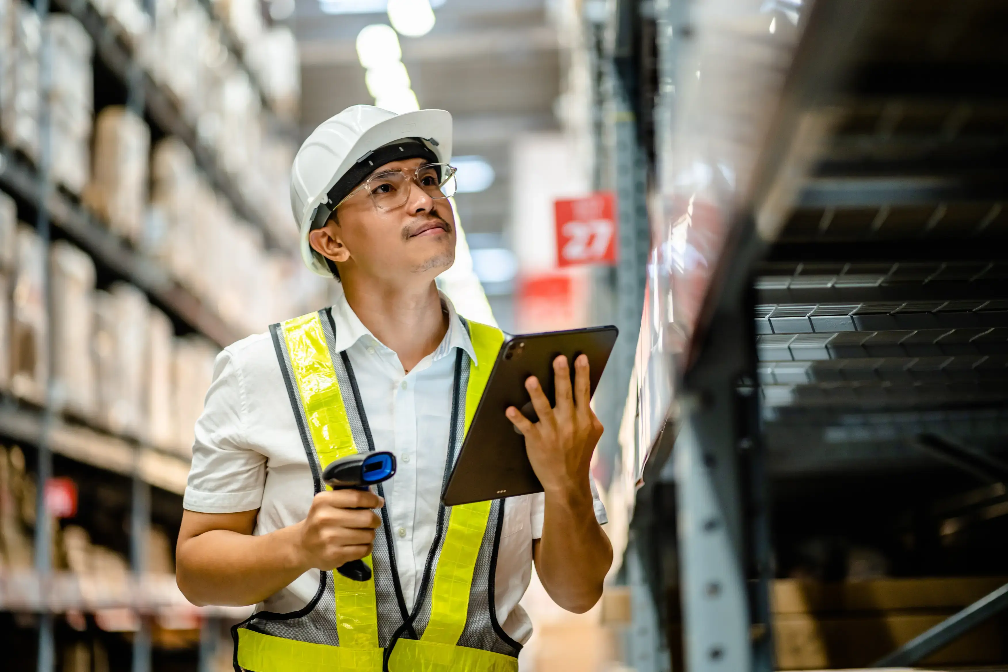 Man useing a digital tablet to check the stock inventory on shelves 