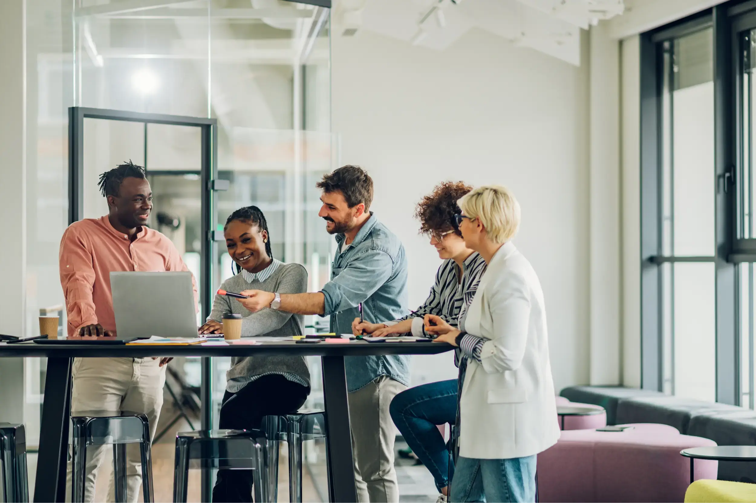 employees gathered around a laptop in the office