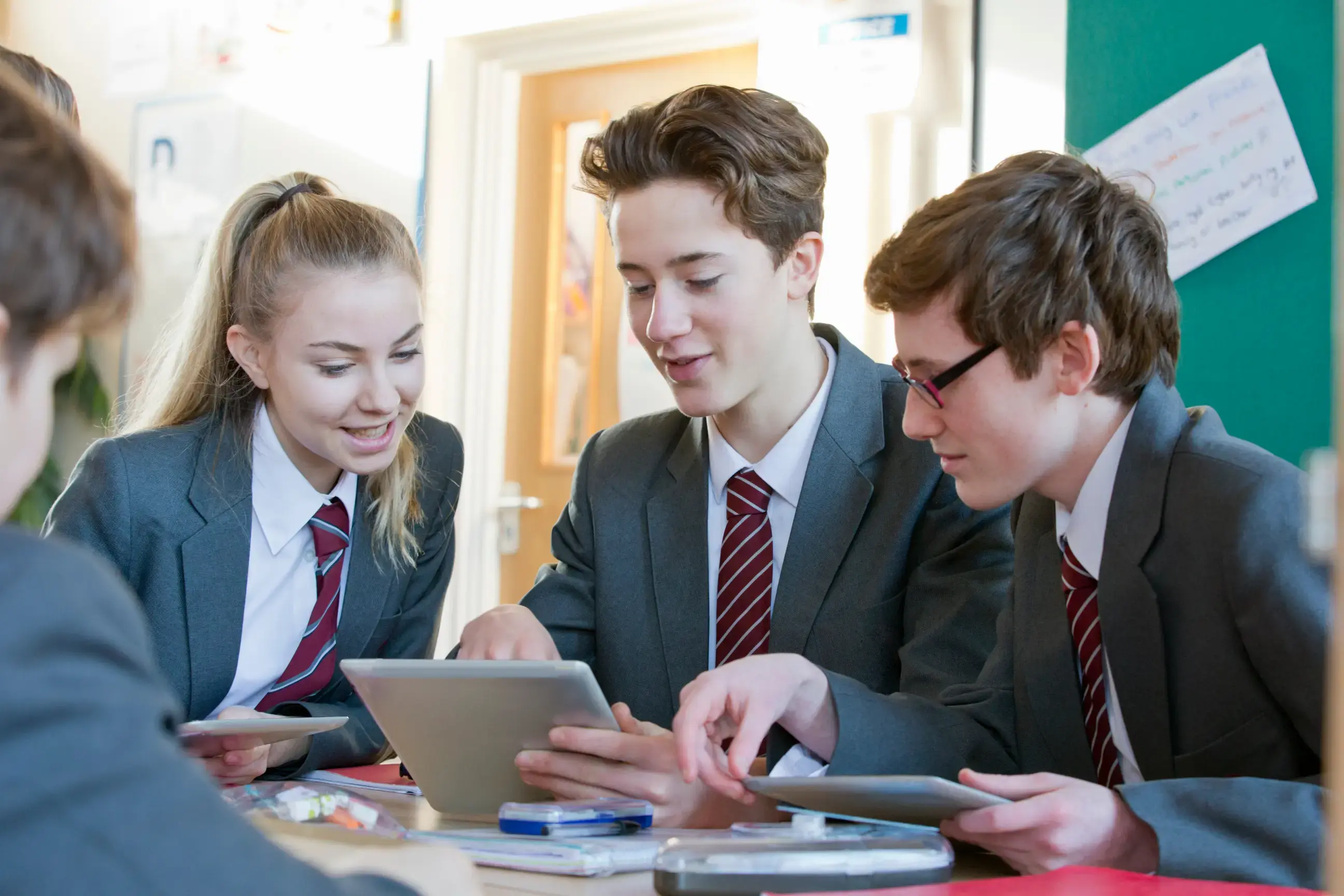 group of high school students using tablet computer in classroom