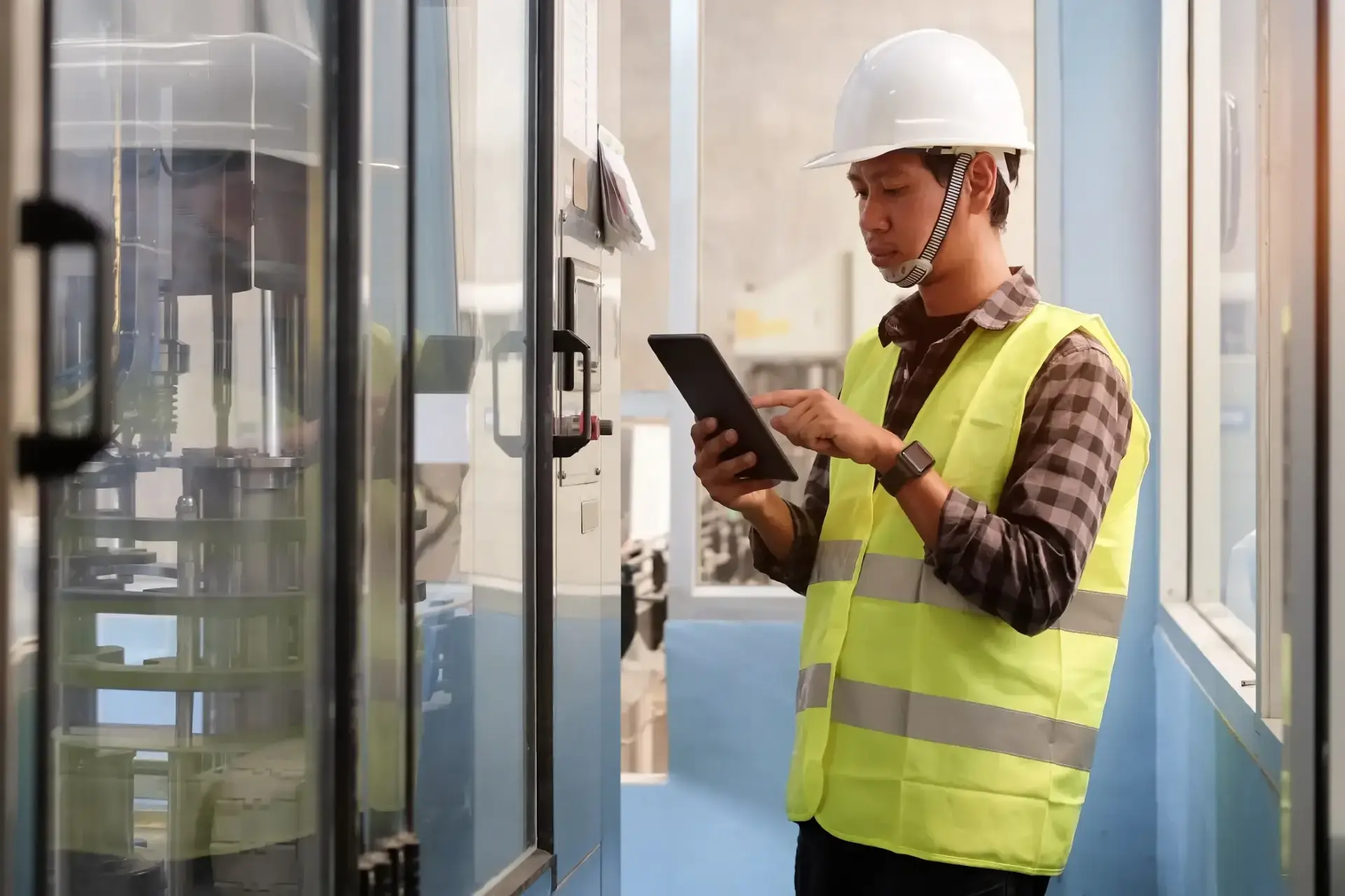 Man in warehouse wearing high vis and using a tablet